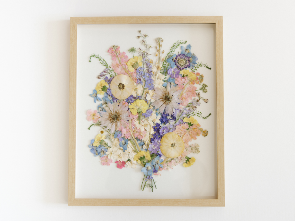 A finished pressed bouquet arranged and framed in light wood