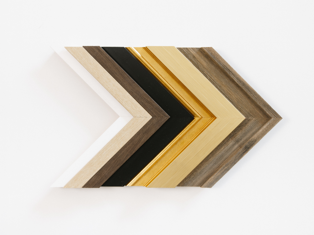 Corner samples of the six frame finishes, fanned out from white through light wood, black, gold and dark wood