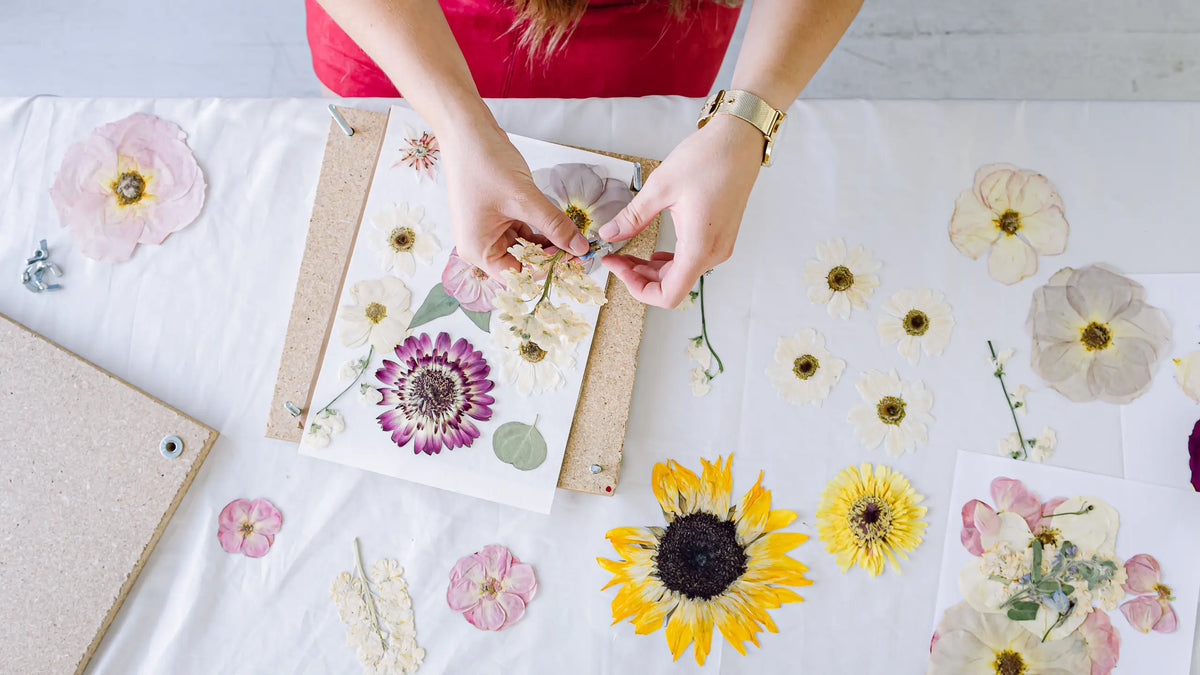 Table of pressed wedding flowers beside wooden flower presses in The Petal Press studio